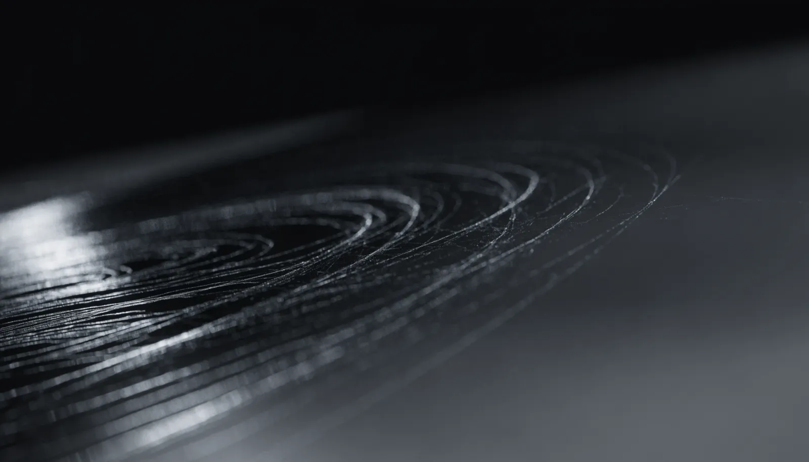Macro view of fine swirl marks catching light across a glossy dark coated paint surface