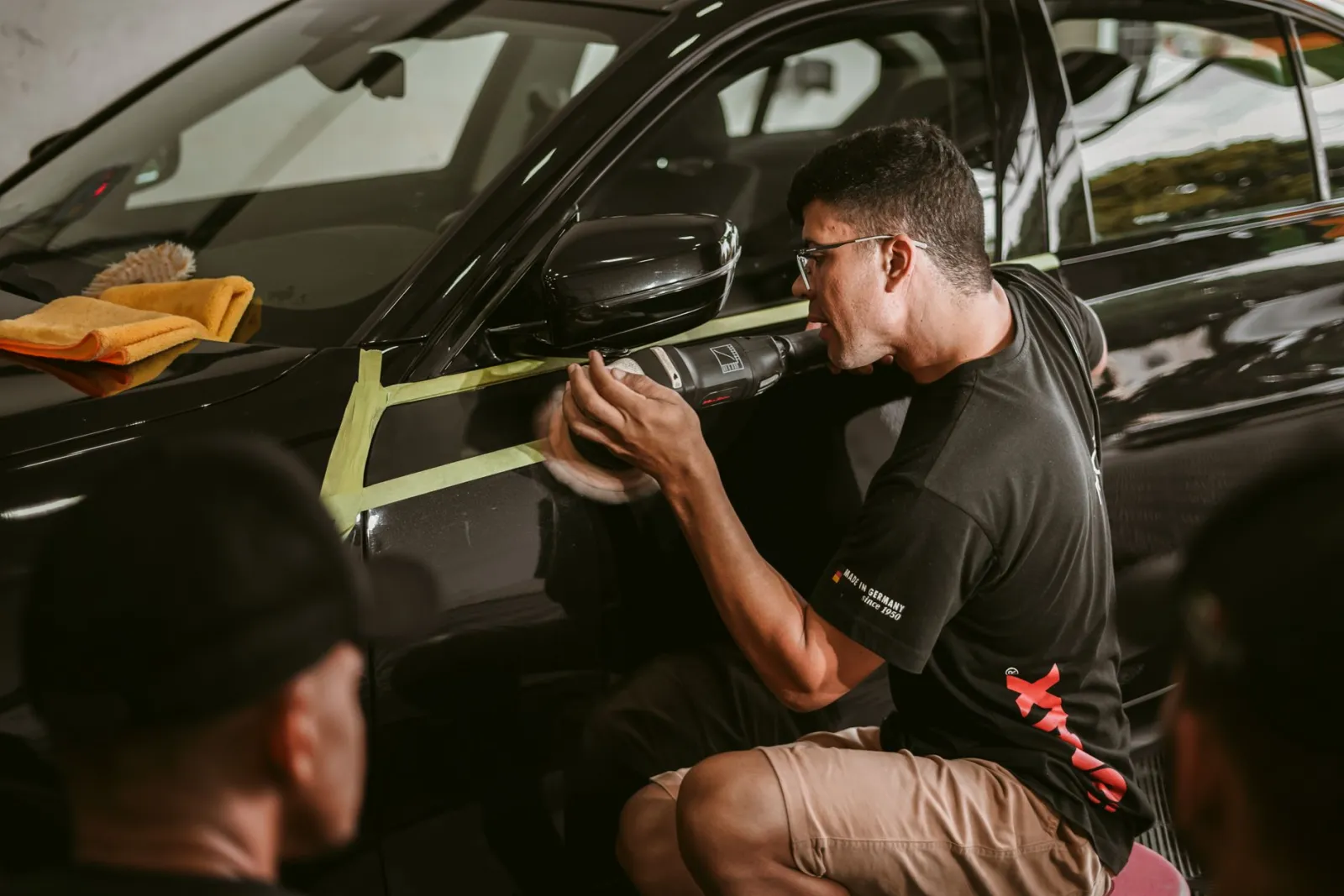 technician machine polishing a vehicle panel in a professional detail bay