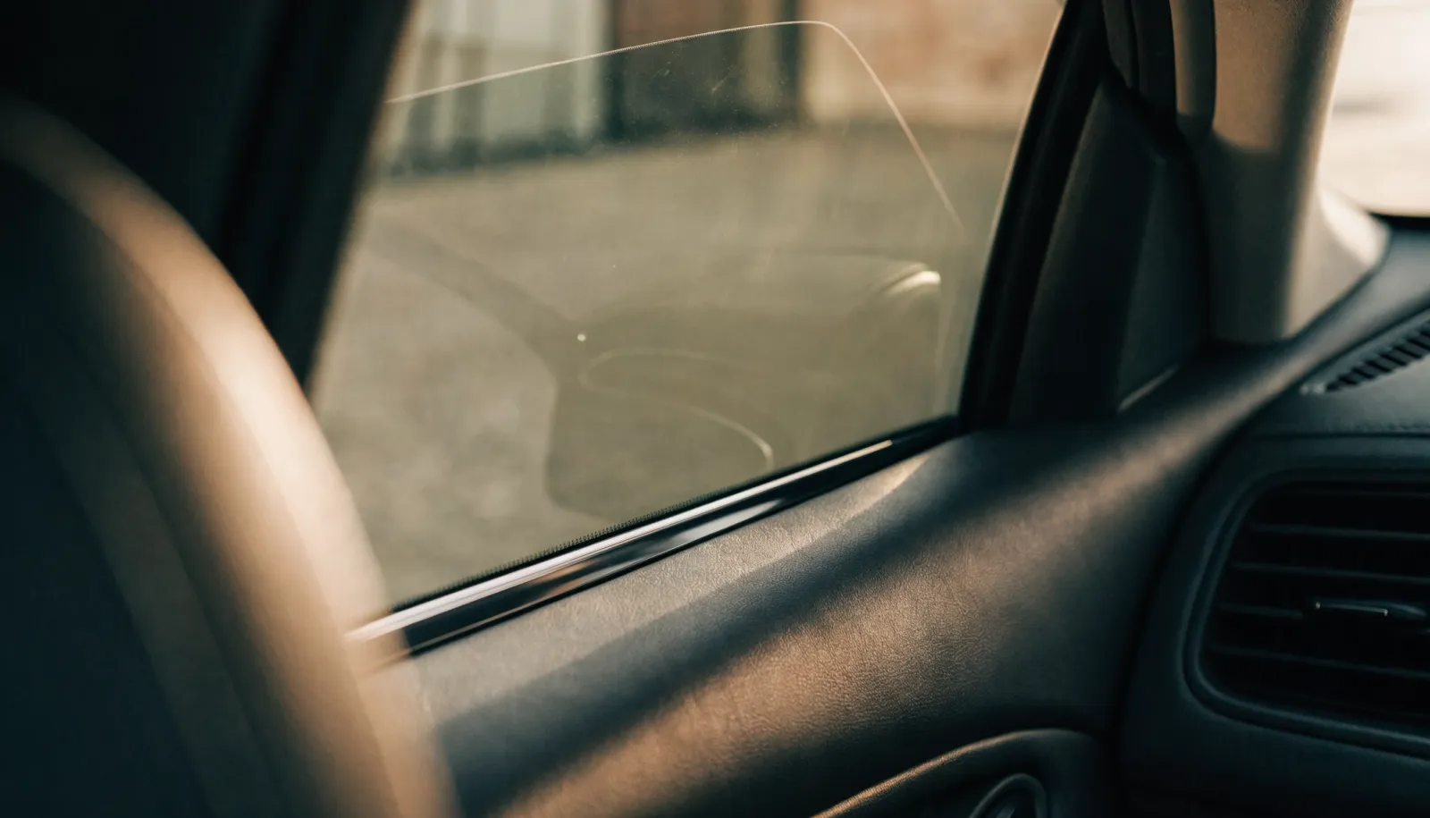 Interior view through a freshly tinted side window with soft light falling across the dashboard