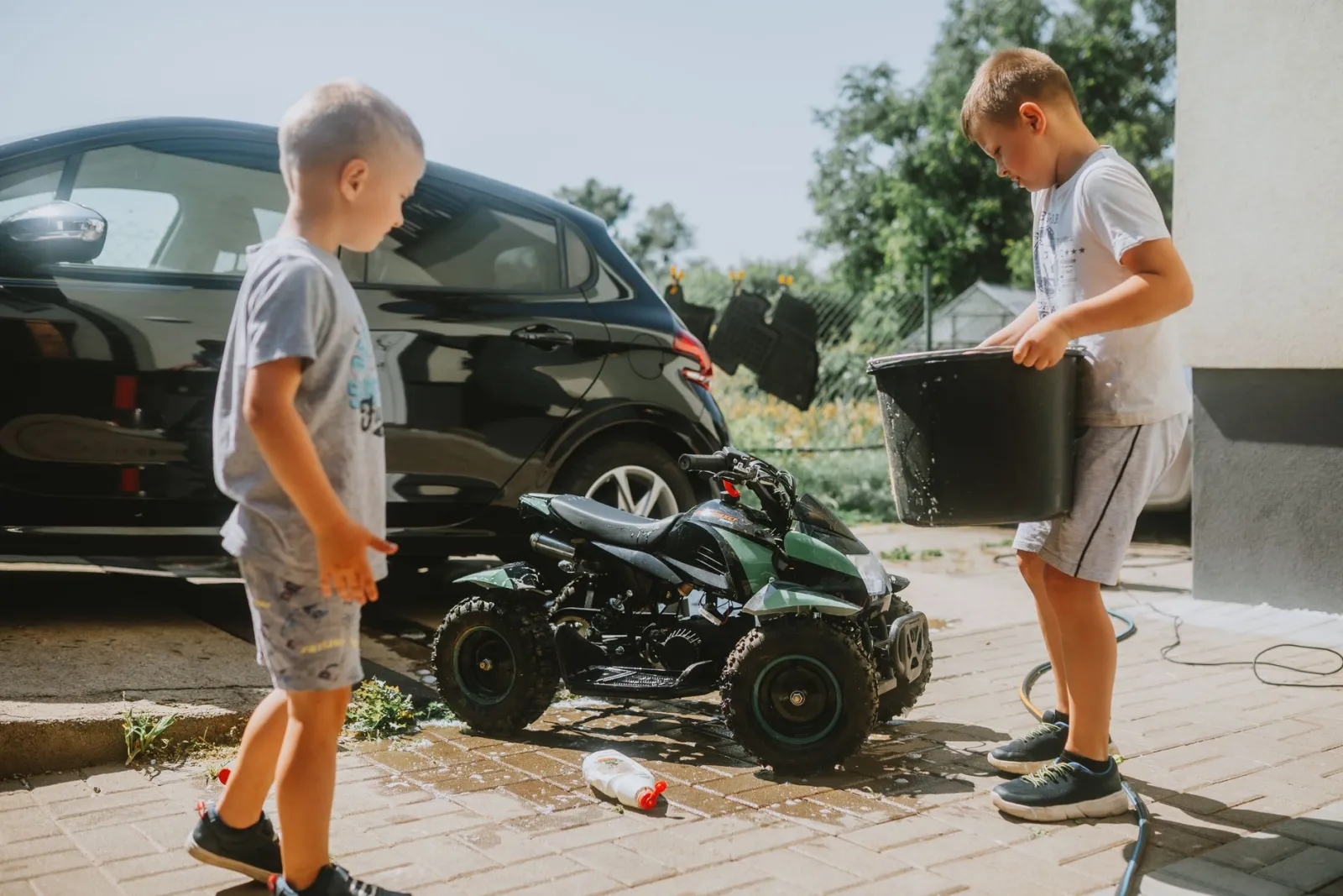 Two wash buckets with grit guards beside a car being hand washed